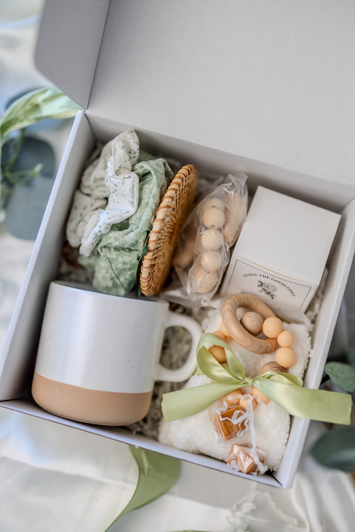 Self-care gift box with white mug, green patterned soap, round woven sponge, and bead soap