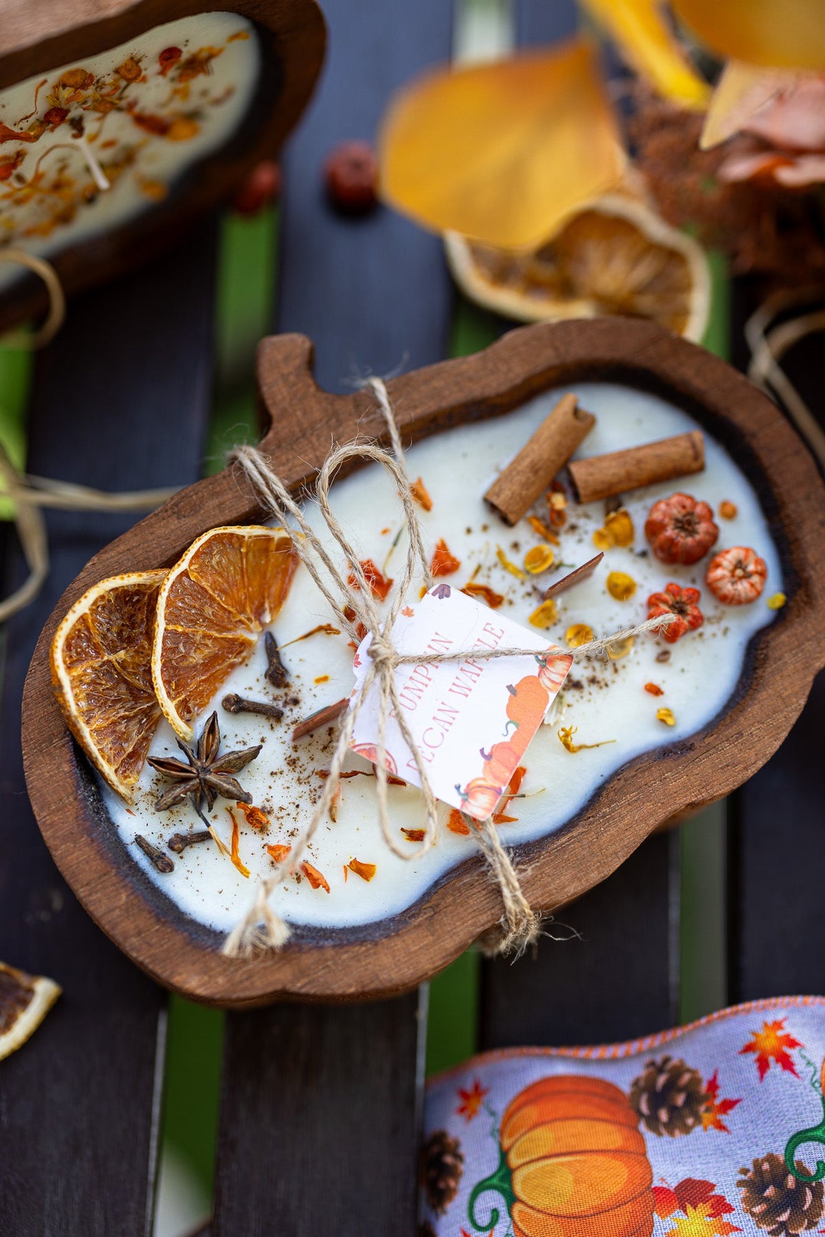 Wooden pumpkin-shaped dough bowl candle with white wax and scattered autumn spices