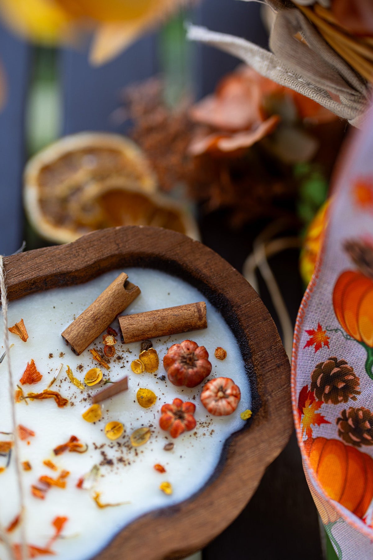 Wooden pumpkin dough bowl candle with white wax and cinnamon sticks, shown in close-up