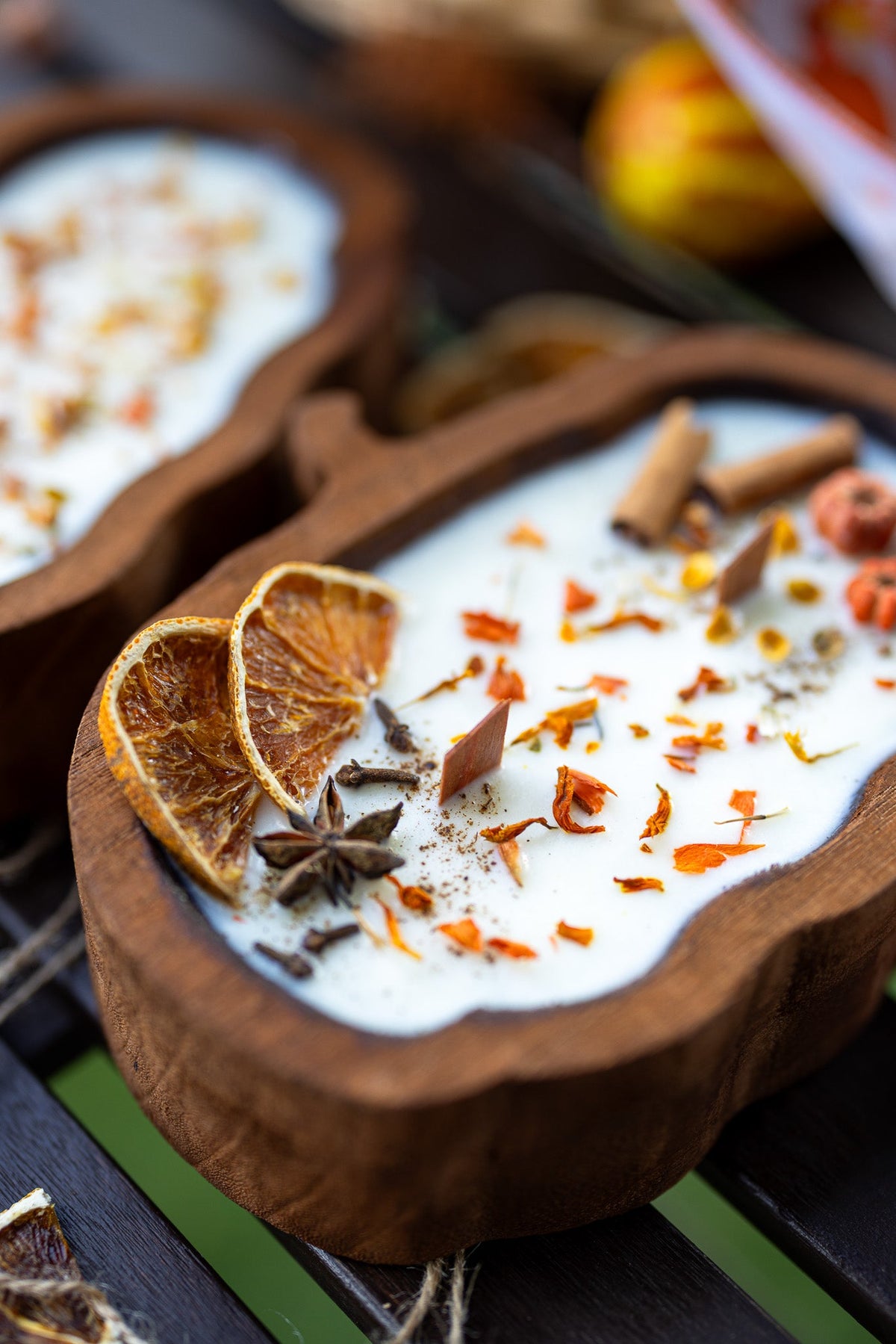 Wooden pumpkin-shaped dough bowl candle with white wax, cinnamon sticks, and spice flakes