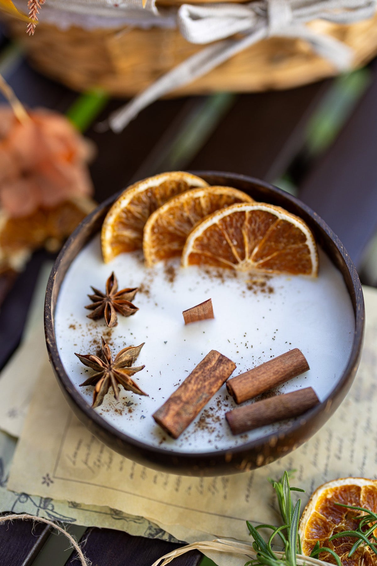 Coconut candle bowl showing white wax with orange slices, cinnamon sticks, and star anise.