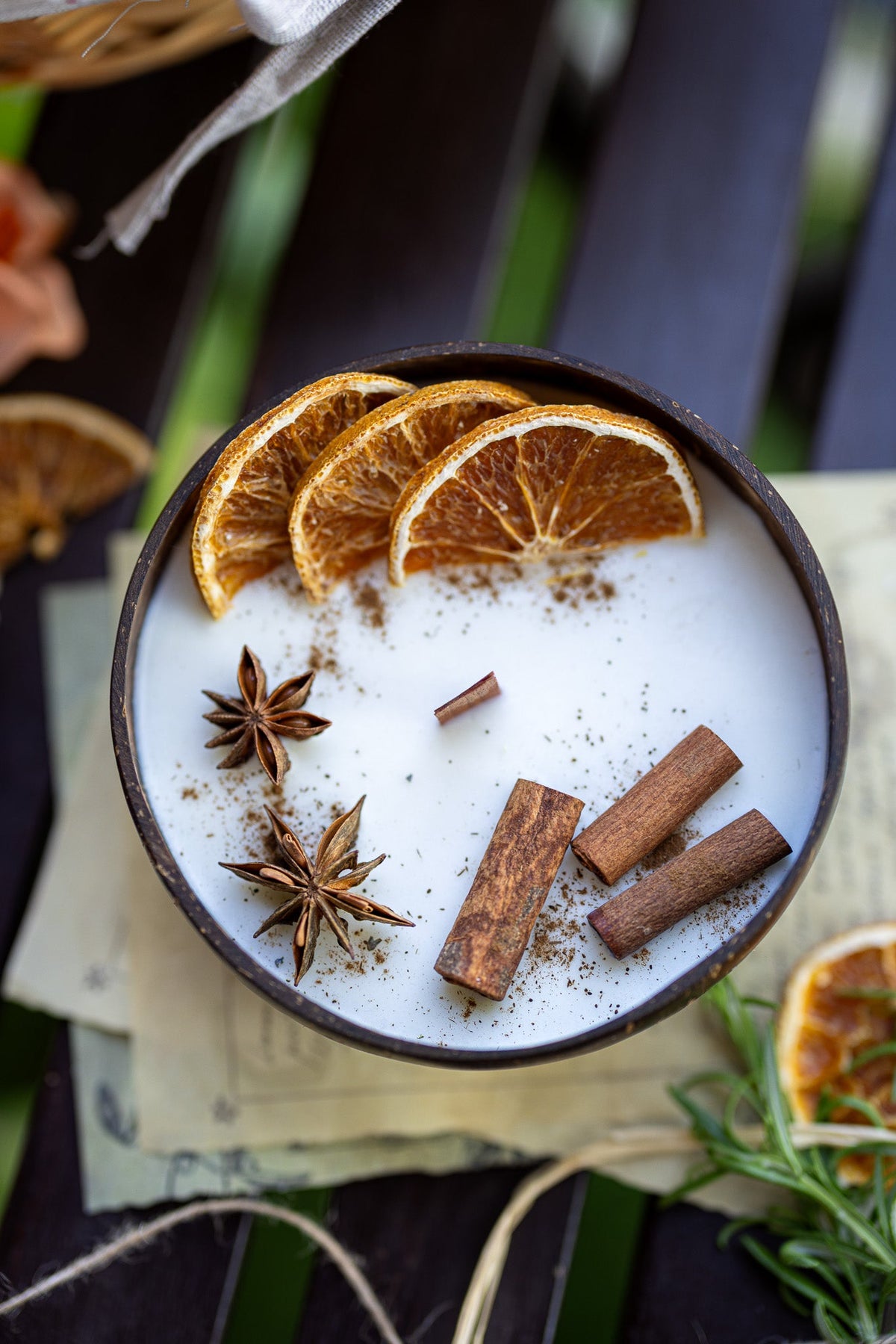 Coconut candle bowl with white wax, layered orange slices, cinnamon sticks, and star anise.