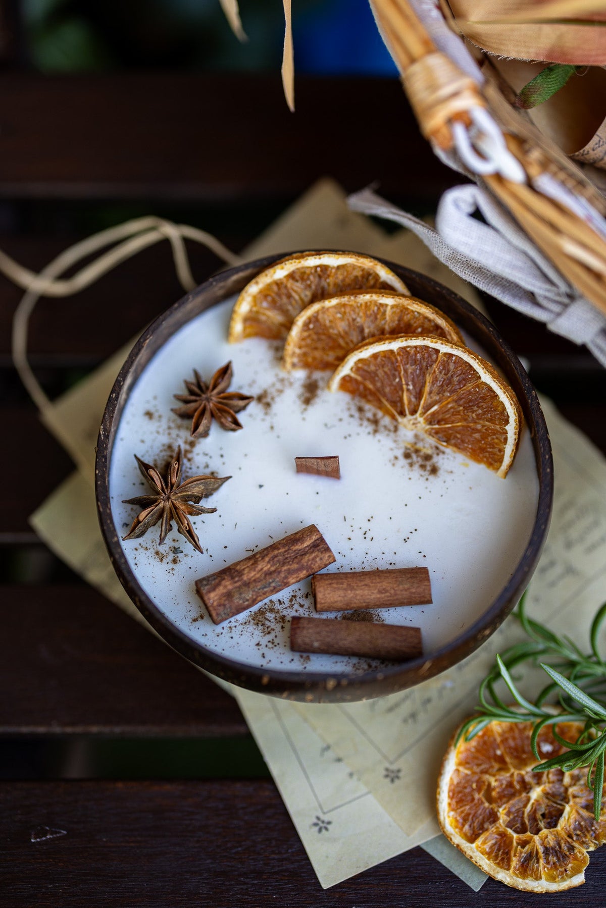 Coconut candle bowl with white wax topped with orange slices, cinnamon sticks, and star anise.
