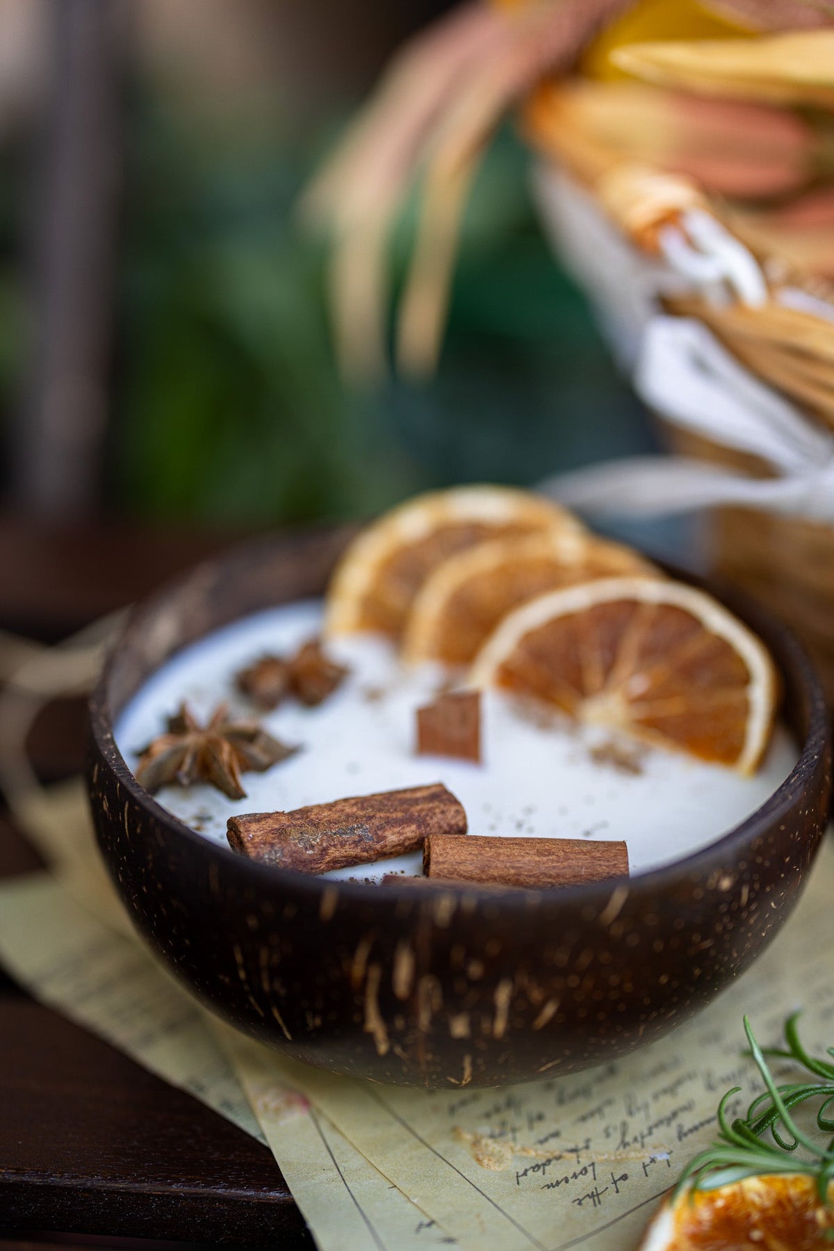 Coconut candle bowl with speckled white wax, orange slices, cinnamon sticks, and star anise.