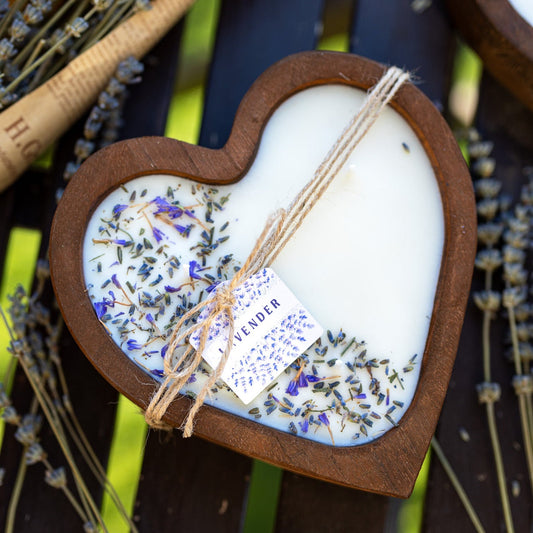 Heart-shaped wood dough bowl candle with white soy wax and scattered lavender buds