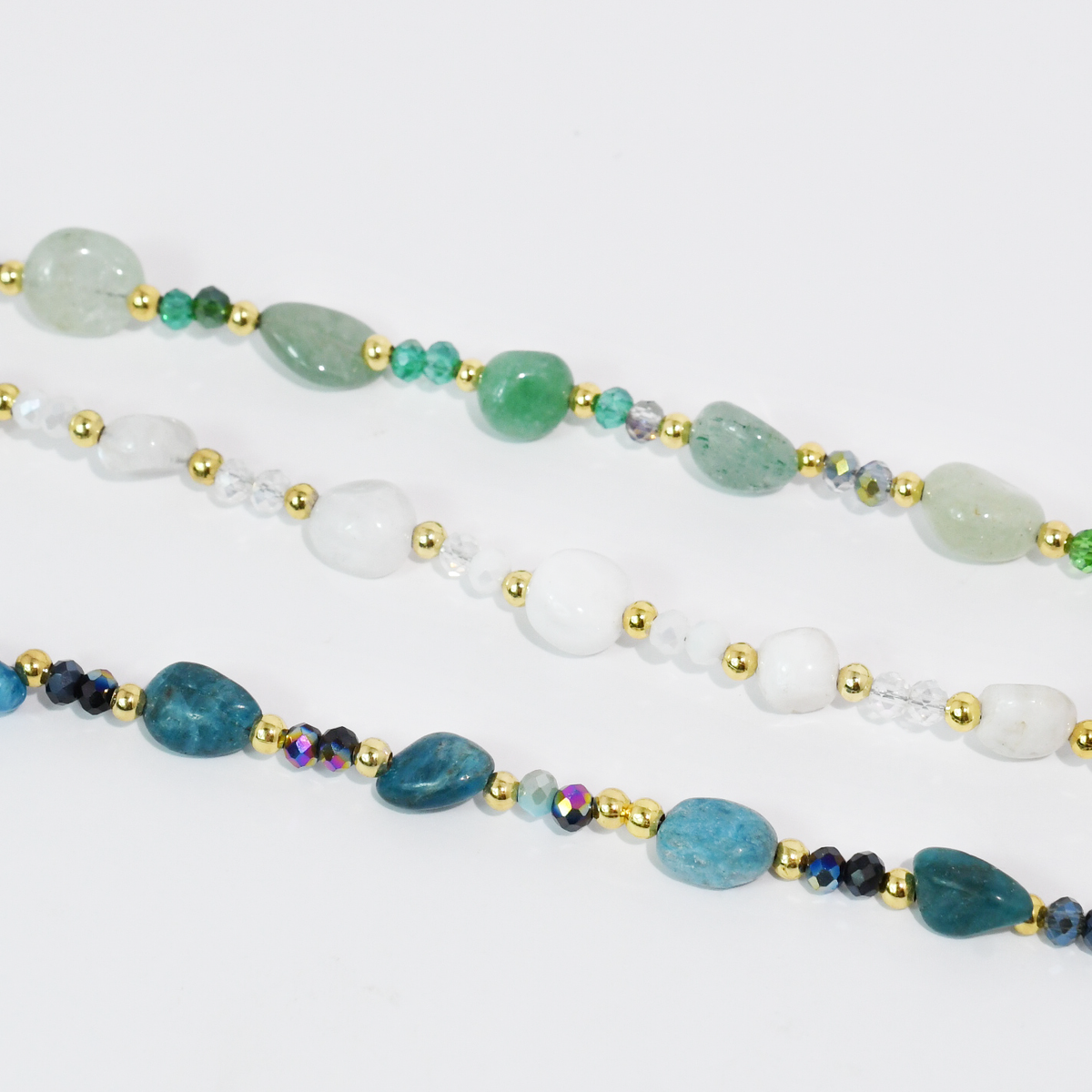 Beaded necklace strands in green, white, and blue with gold-tone beads and spacer accents.
