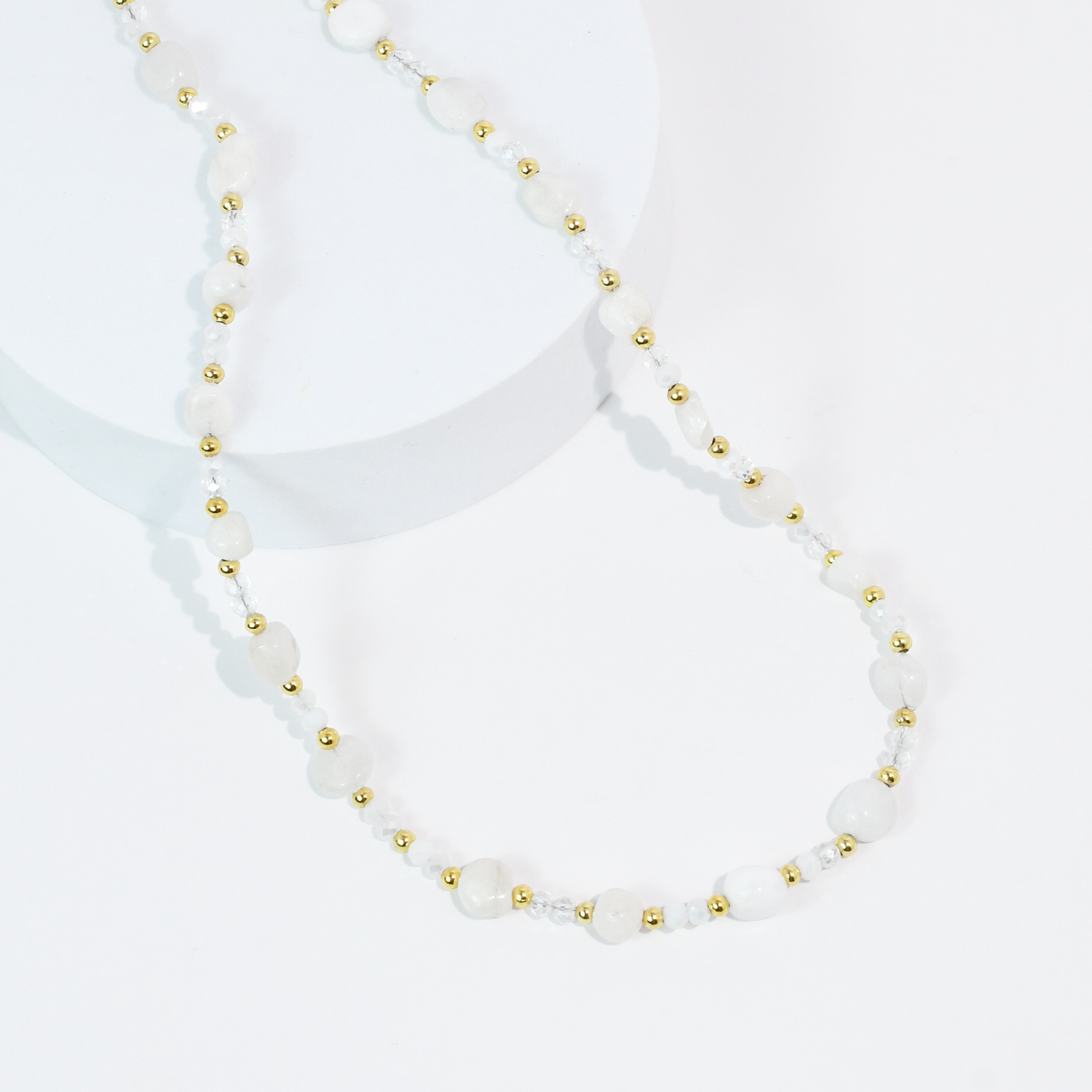 White beaded necklace with oval white stones and gold-tone bead spacers.