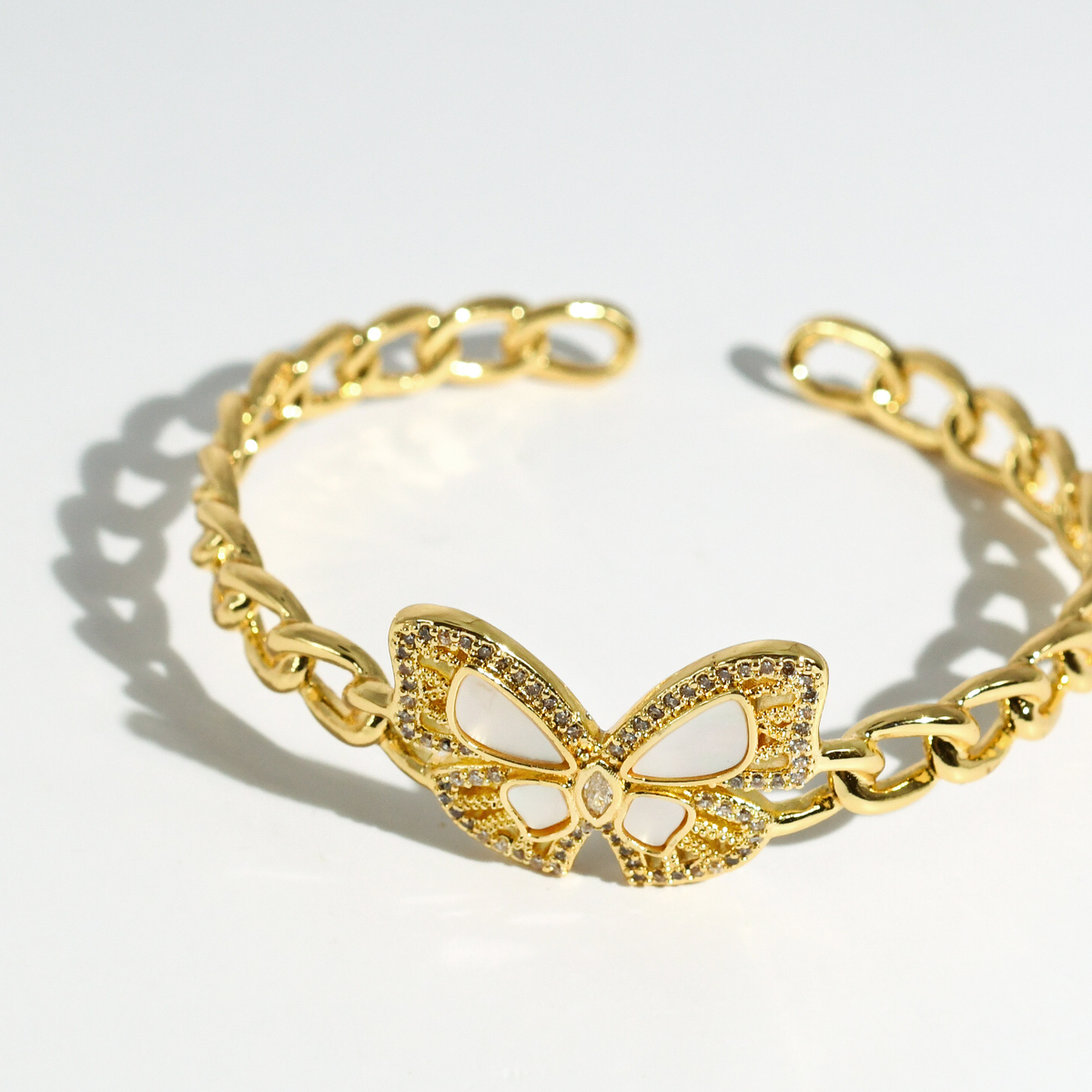 Gold-tone wrap bangle bracelet with centered butterfly charm on chain.