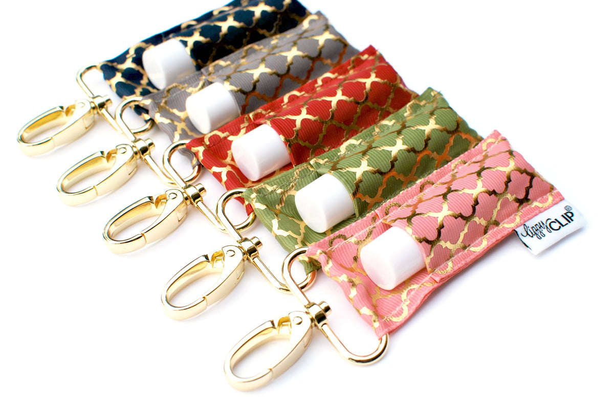 Assorted quatrefoil lip balm holders with gold keychain clips and white balm tubes