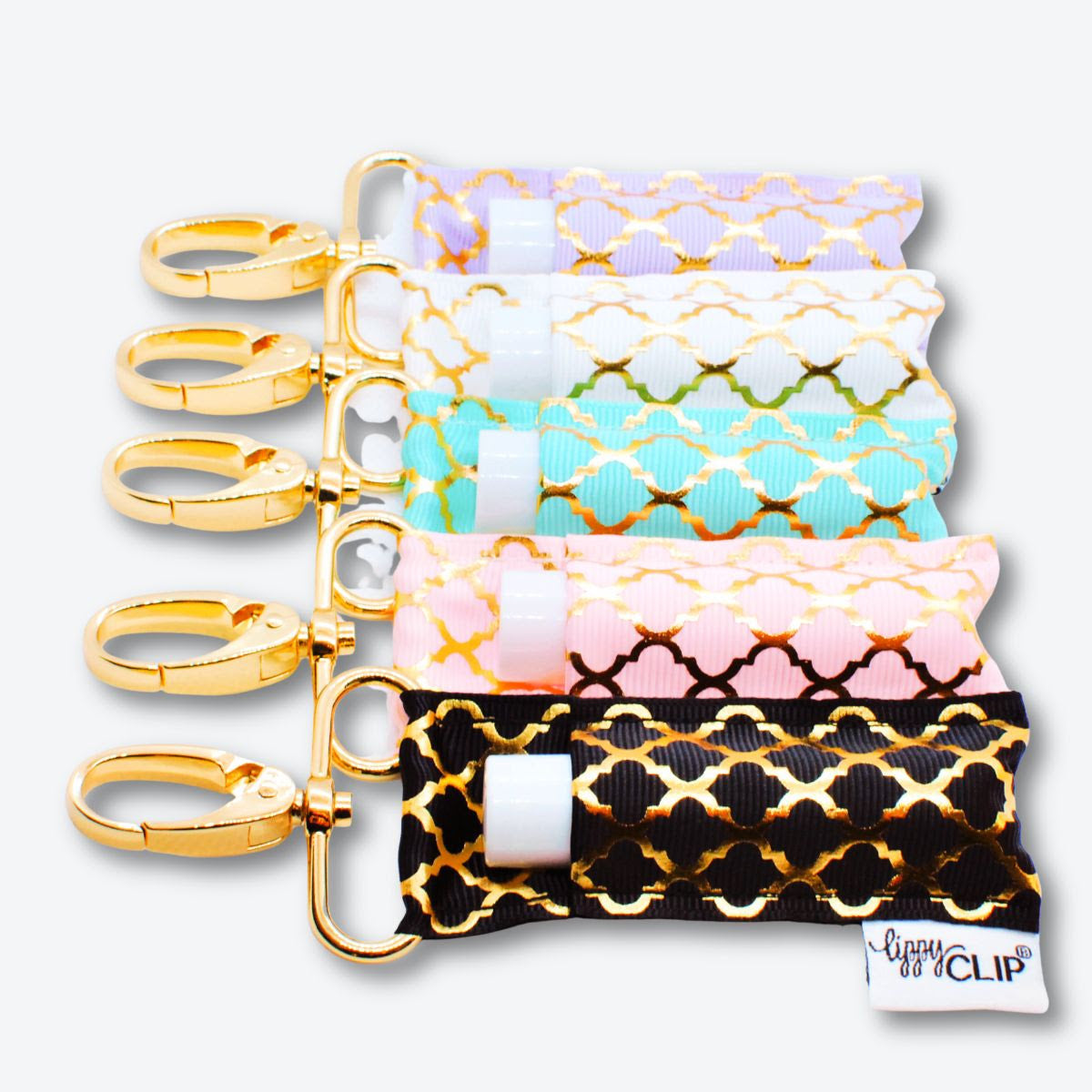 Assorted quatrefoil lippyclip holders with gold keyrings, shown in multiple colors