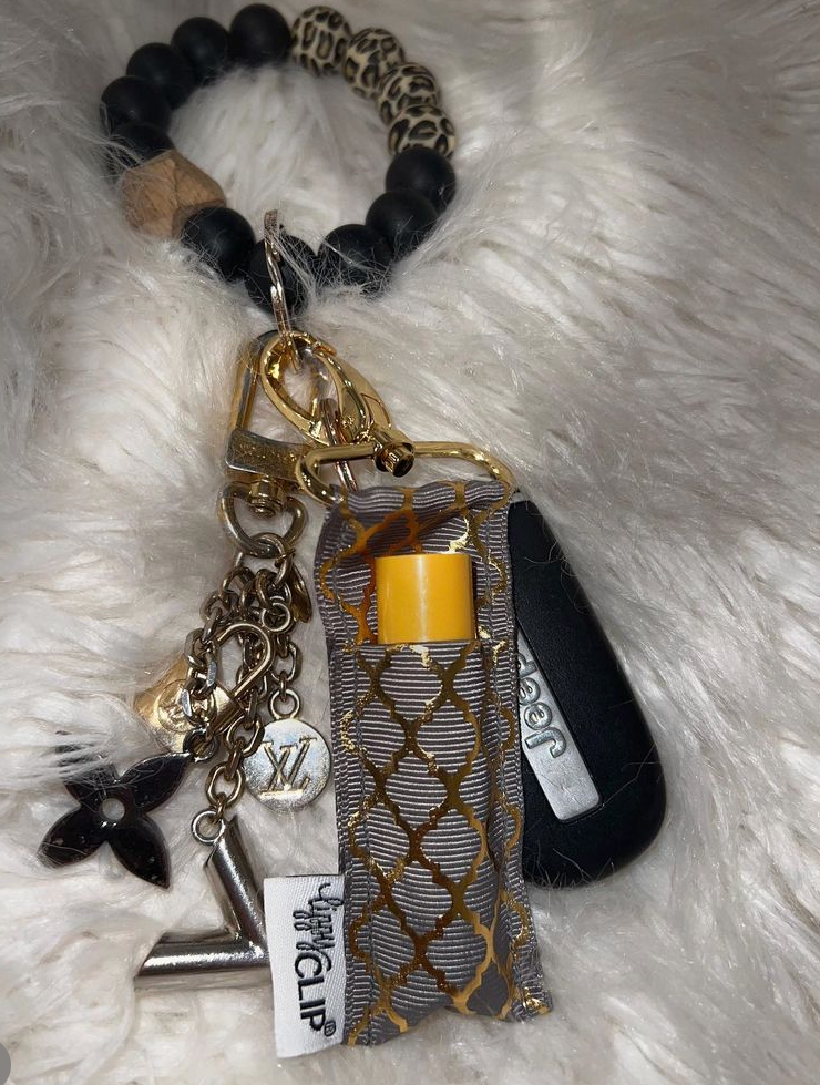 Leopard-pattern LippyClip® lip balm holder with gold keychain charms and dark balm