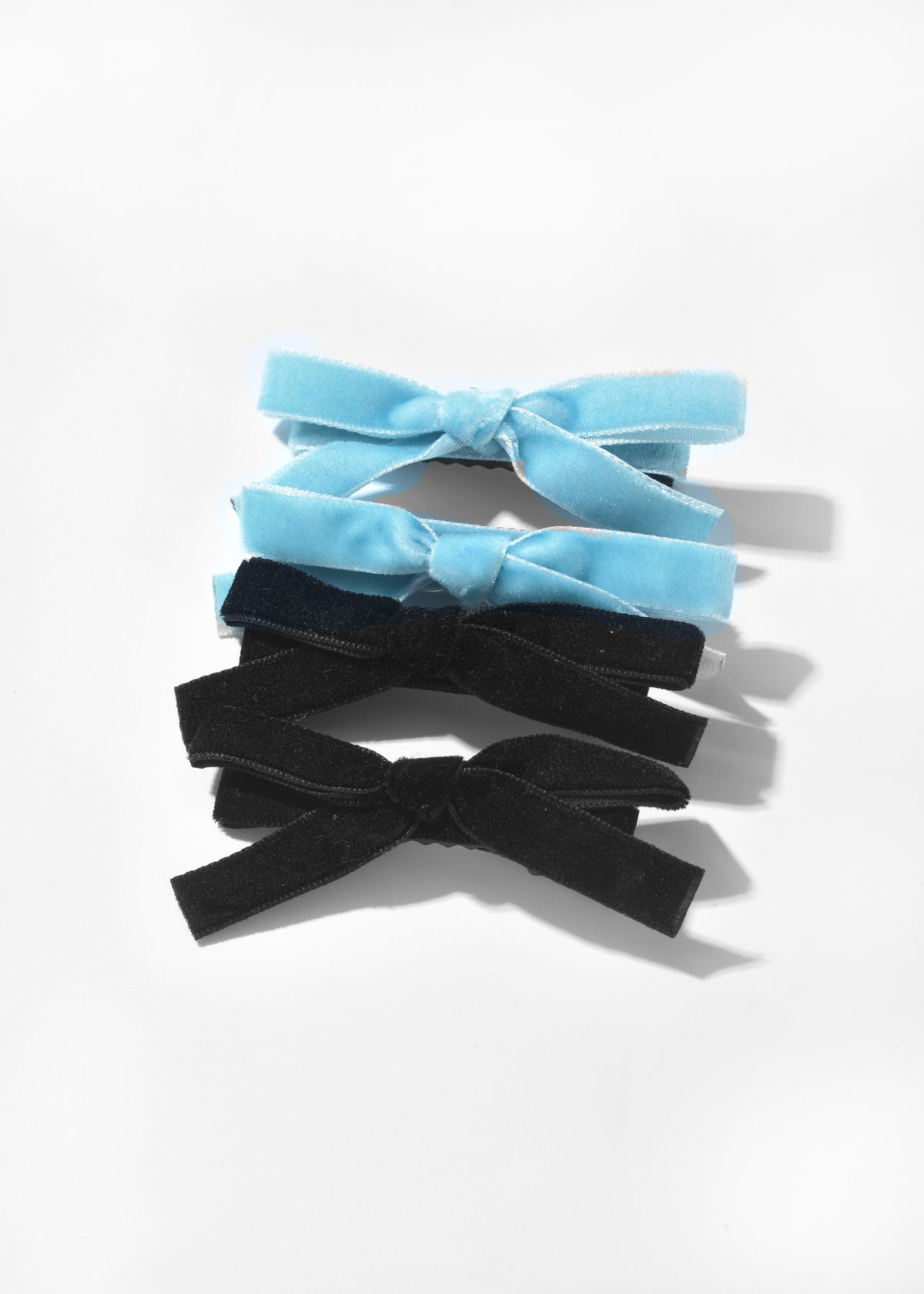 Velvet bow hair clips in blue and black, shown in a stack of four.