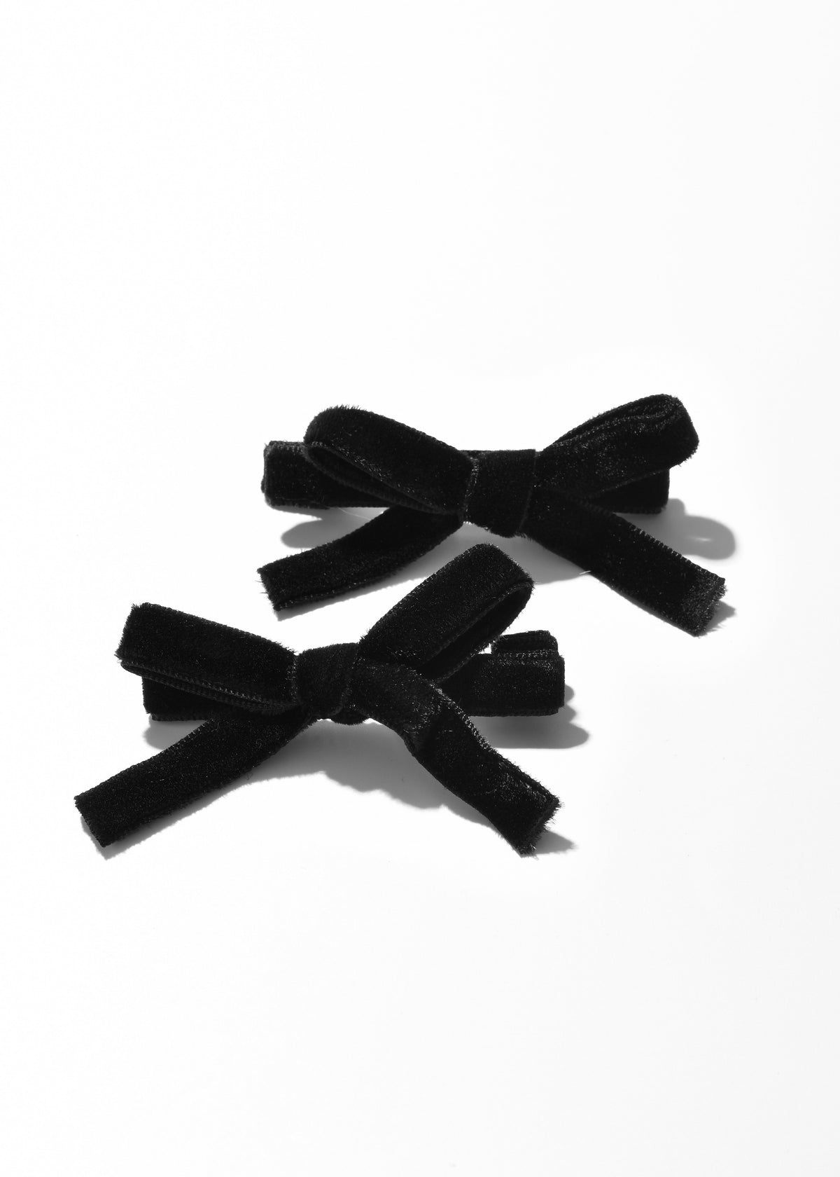 Two black velvet bow hair clips shown from above.