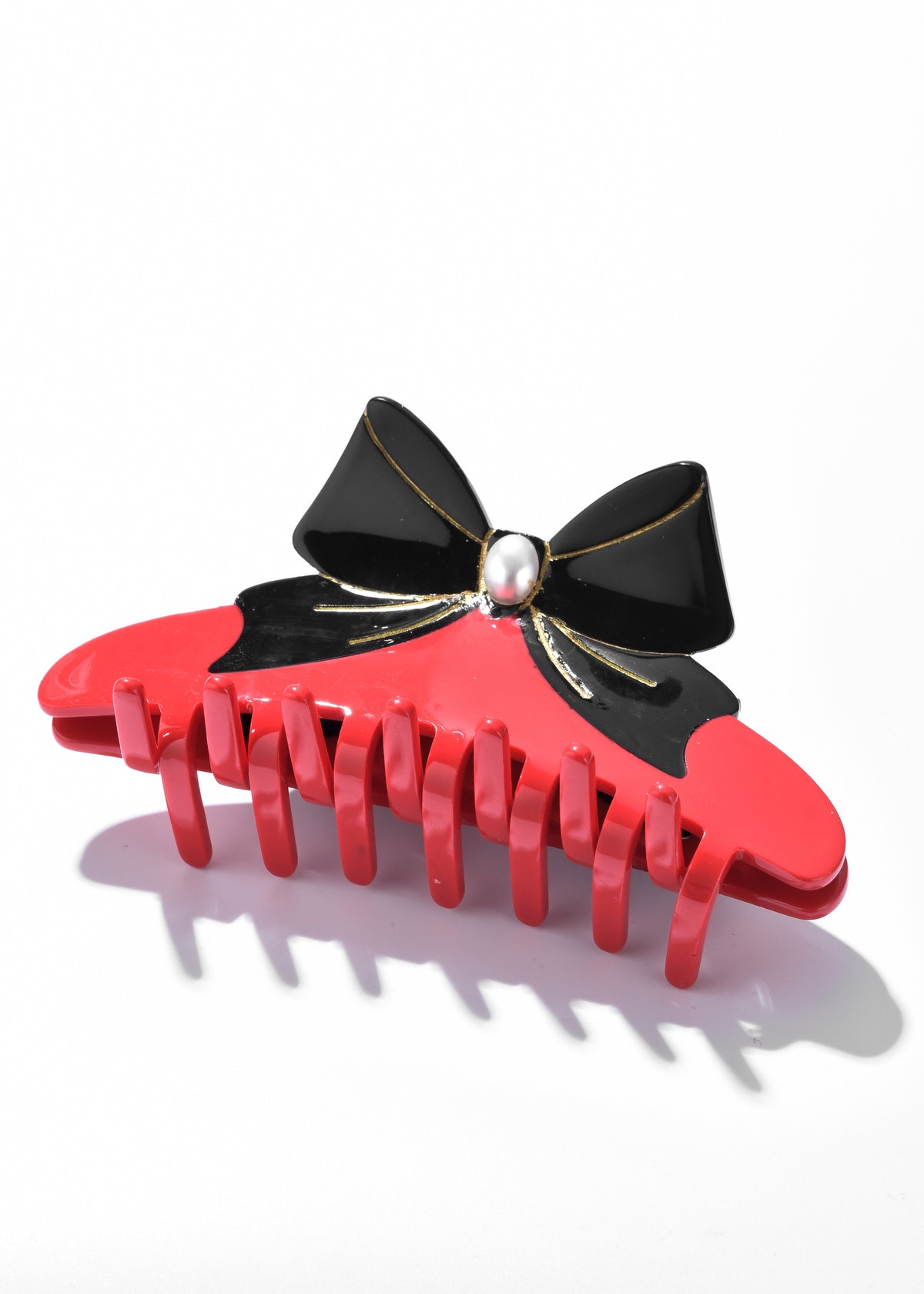 Red claw clip with a black bow, gold accents, and a pearl-like center
