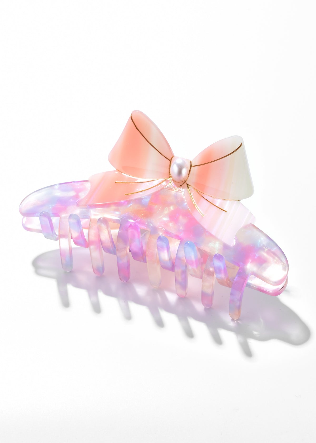 Iridescent claw clip with a peach-pink bow and pearl-like center
