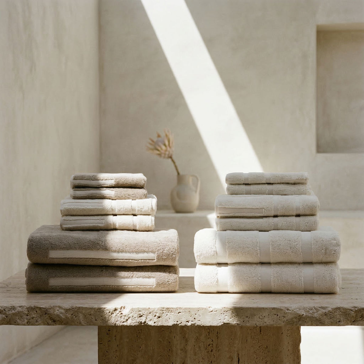 Light beige and gray terry towel set, folded in stacks with striped borders.