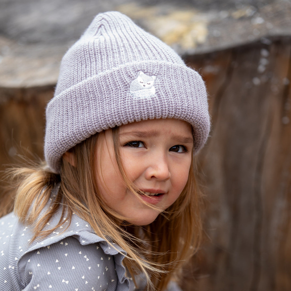 Gray knitted beanie with fox embroidery worn by a child, front view