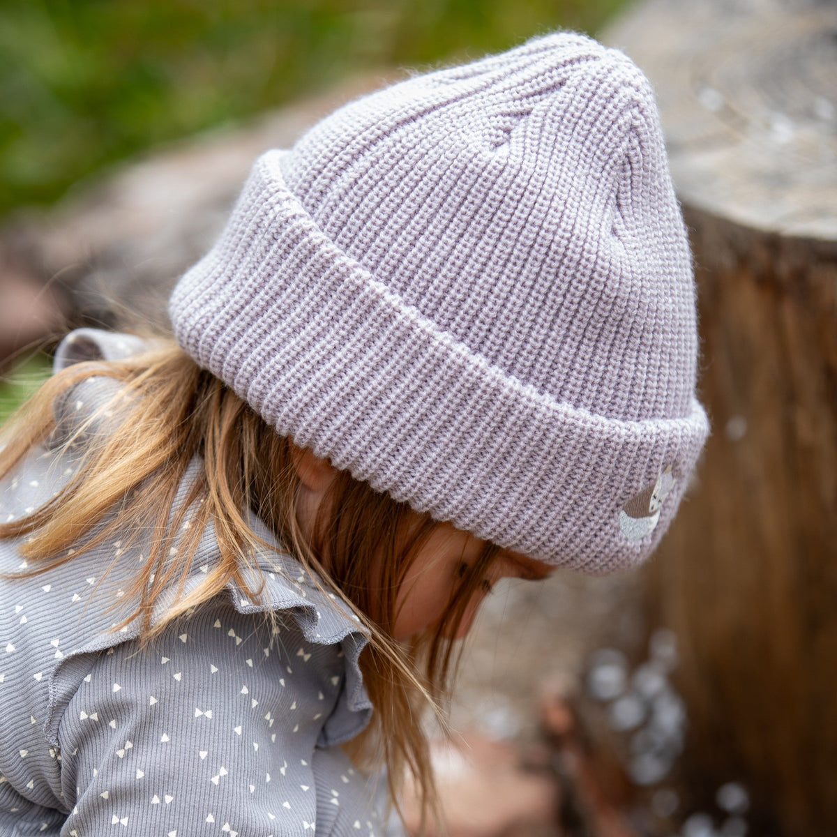 Side view of a child wearing a gray knitted beanie with folded cuff