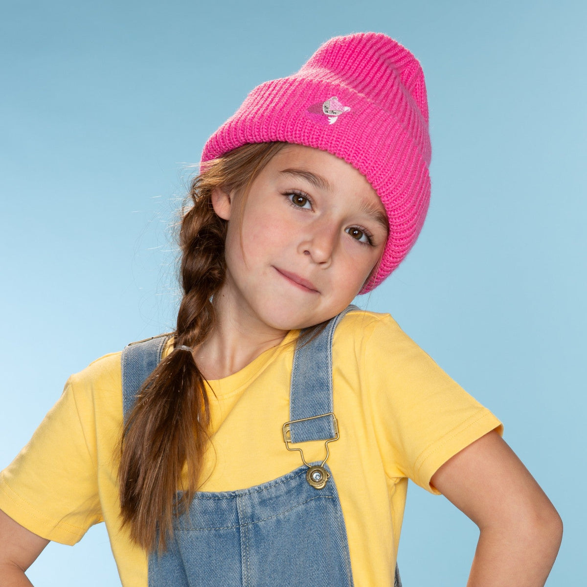 Bright pink knitted beanie with a fox patch, worn on a child