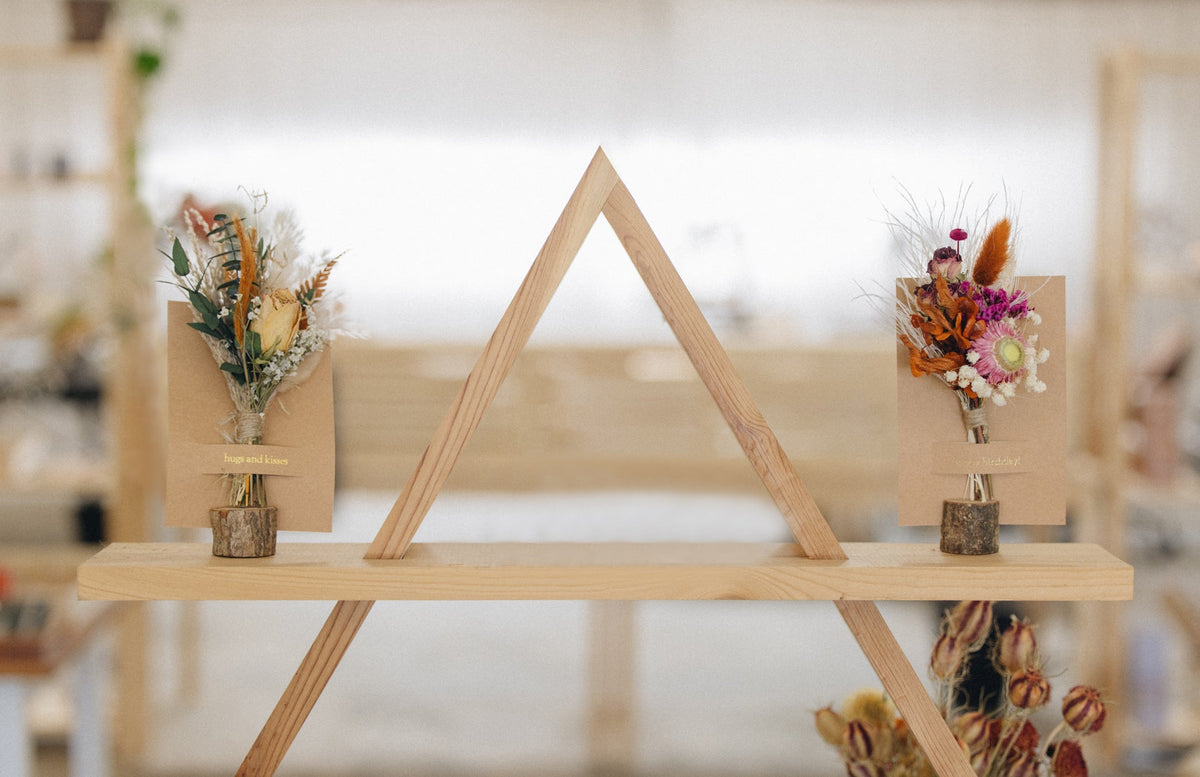 Mini dried floral greeting card display on wooden stand with three kraft envelope bouquets