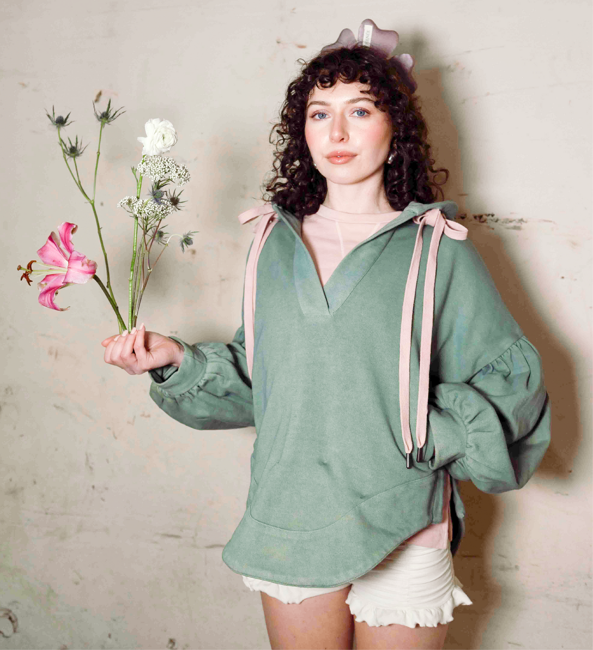 Sage green Harmony Hoodie with pink drawstrings, V-neck, kangaroo pocket, and gathered sleeves.