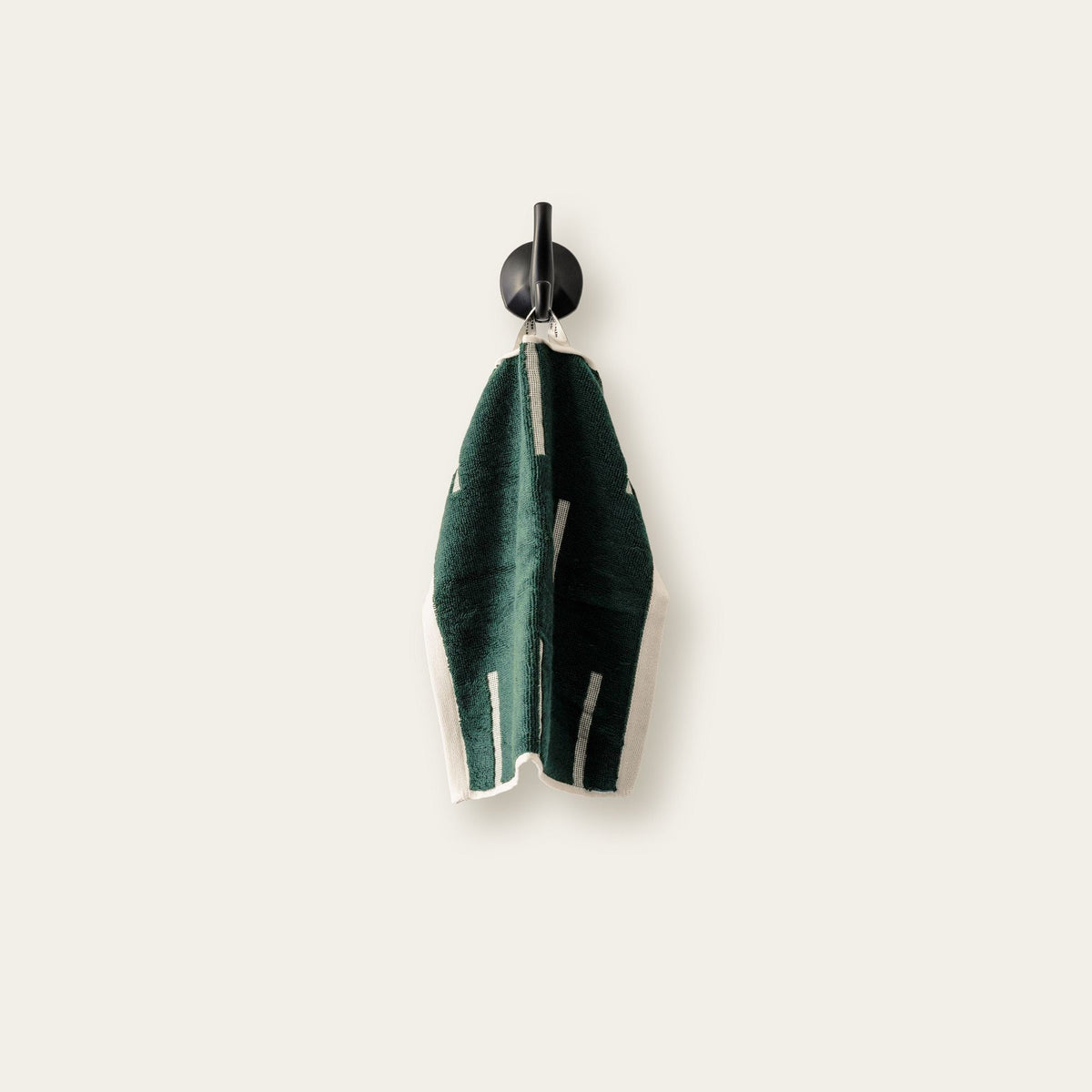 Dark green cotton towel hanging, showing ecru stripe detail along the edge