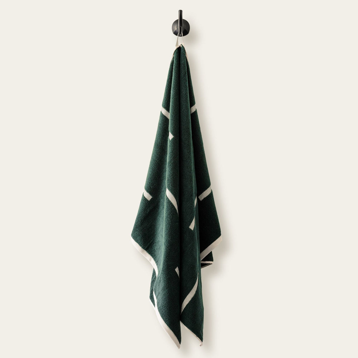 Dark green cotton towel hanging with ecru stripe accents at the edges