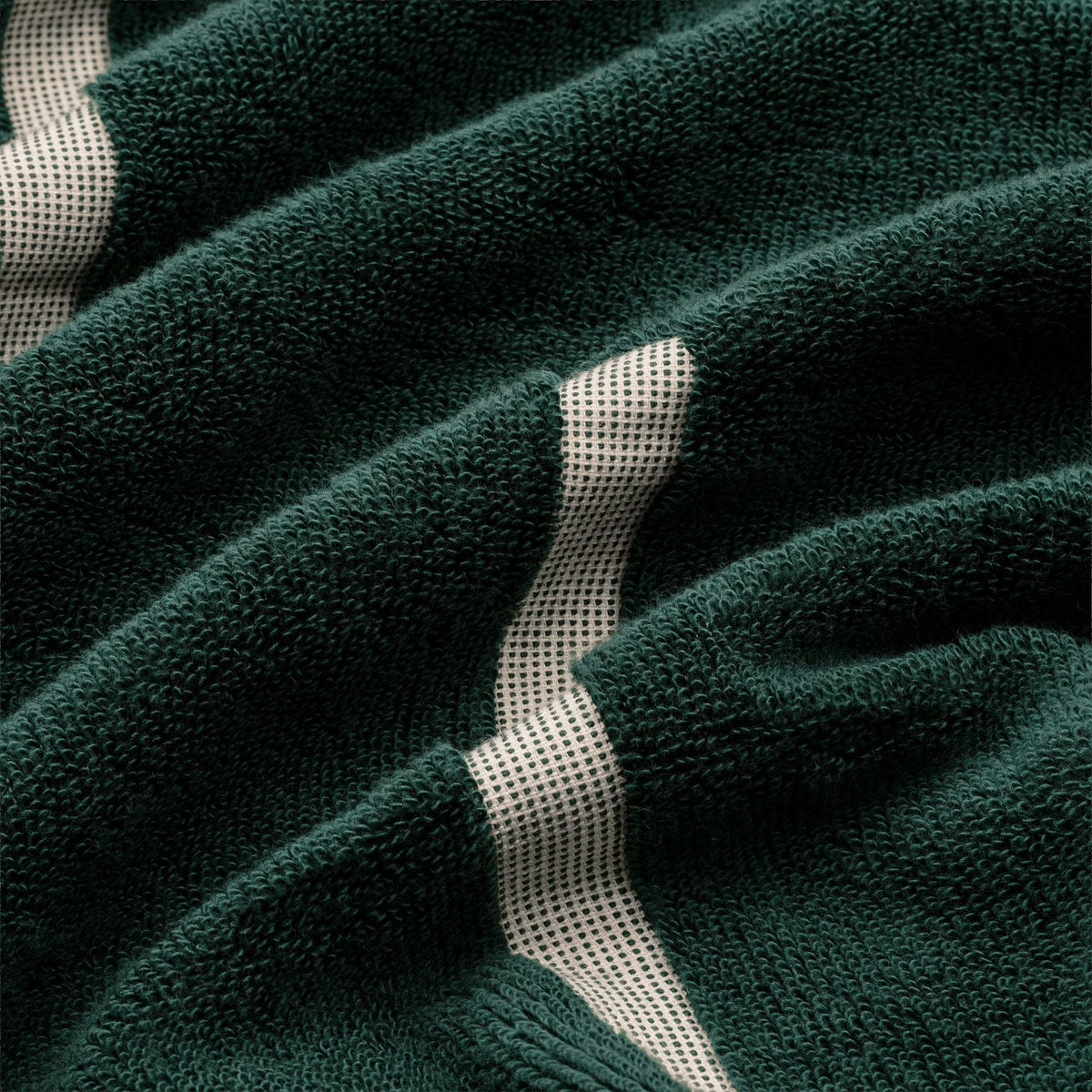 Close-up of dark green cotton towel texture with ecru stripe sections