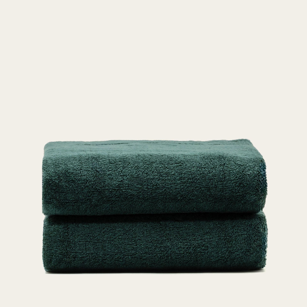Stacked cotton towels in dark green, solid color with plush terry texture