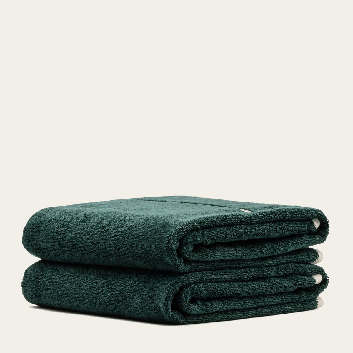 Folded dark green cotton towels with plush texture and visible corner stripe