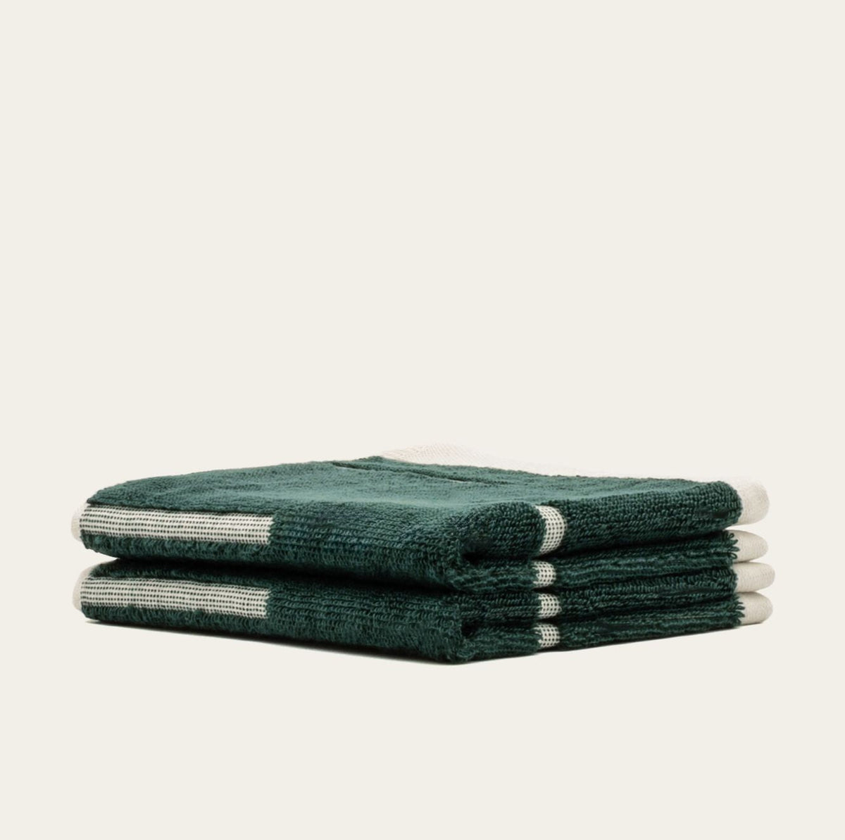 Folded cotton towels in dark green with ecru stripe panels, stacked