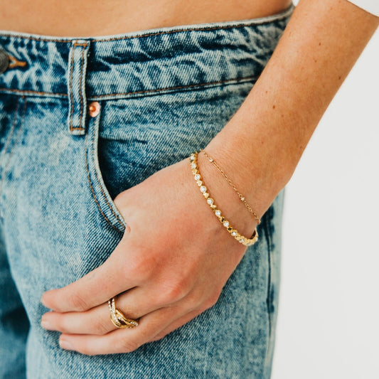 Gold hinge bracelet with heart charms and diamond-like stones on wrist