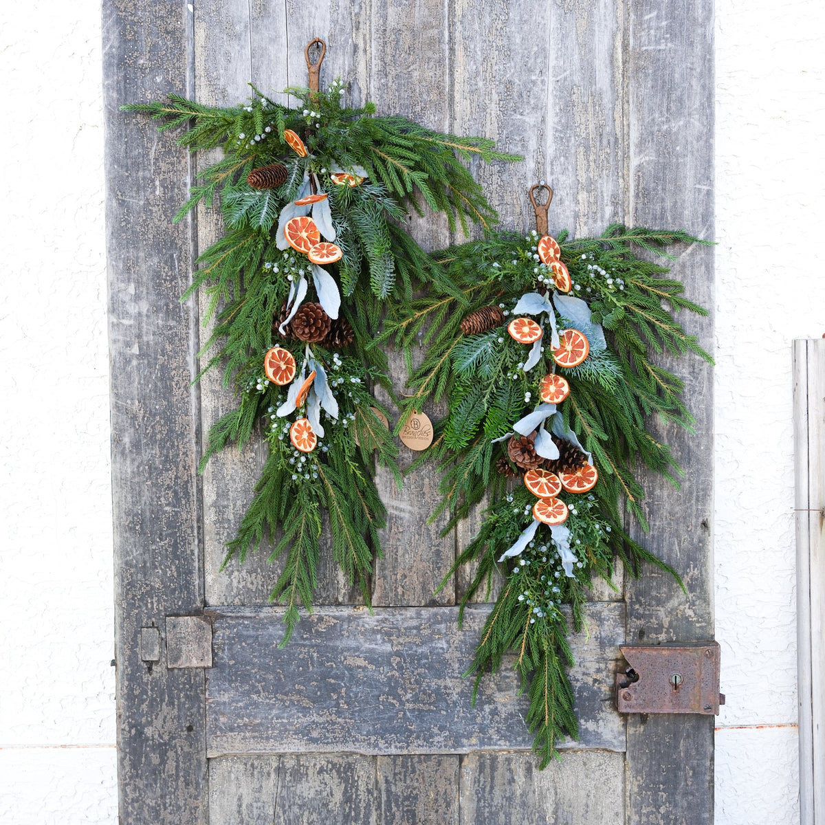 Evergreen holiday drop garland with orange slice ornaments, pinecones, and white ribbon tails