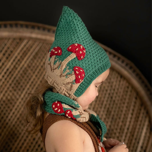 Hunter green pixie hat with red mushrooms and beige cuff, worn with ties