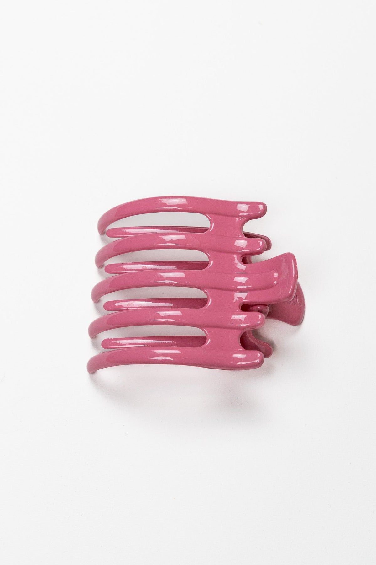 Wide lay-down hair claw, shiny magenta-pink with three ridged teeth