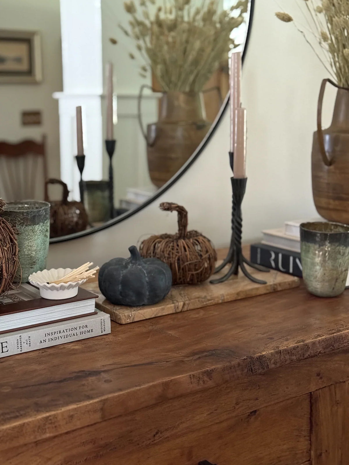 Small dark decorative pumpkin on a wooden console with other home accents nearby