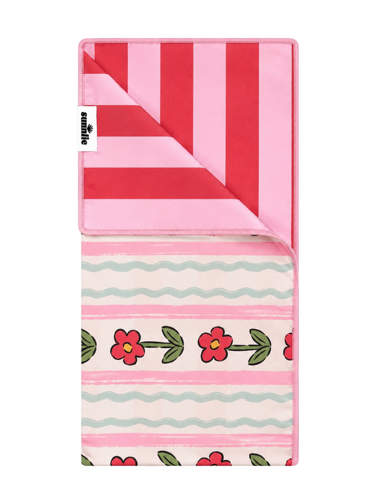 Pink quick-dry towel with red stripes, wavy border, and red flower pattern