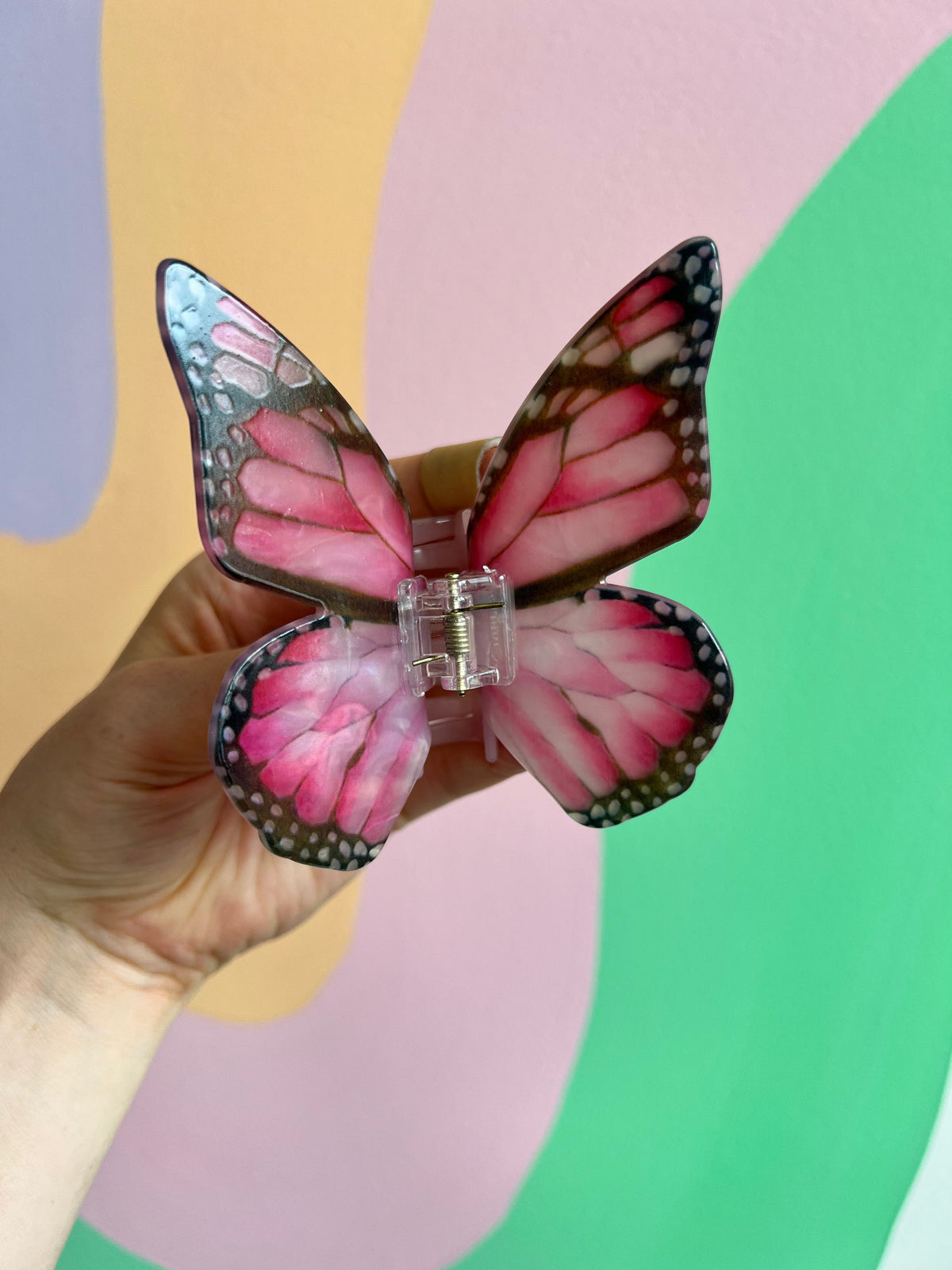 Pink butterfly hair claw with dark red accents and a central metal clasp
