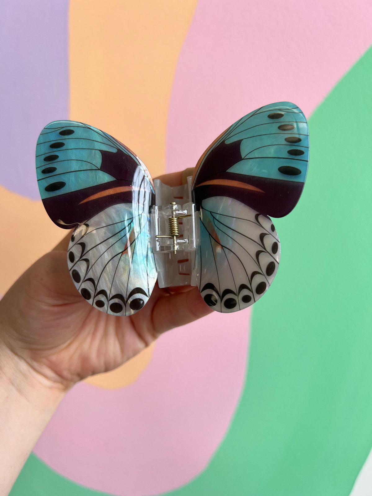Multicolor butterfly hair claw with teal top wings and white patterned bottom wings