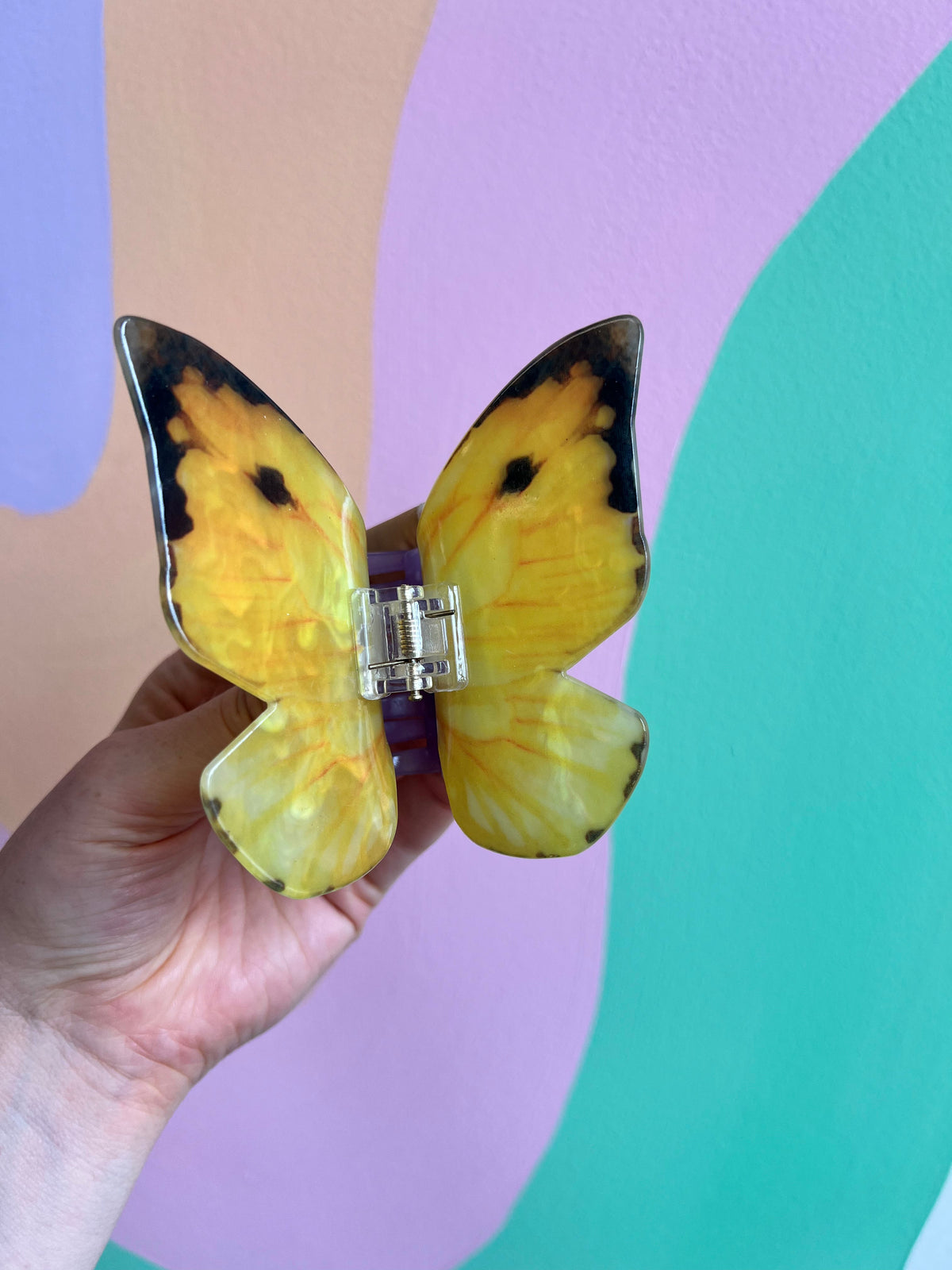 Yellow butterfly hair claw with dark accents and a central metal clasp