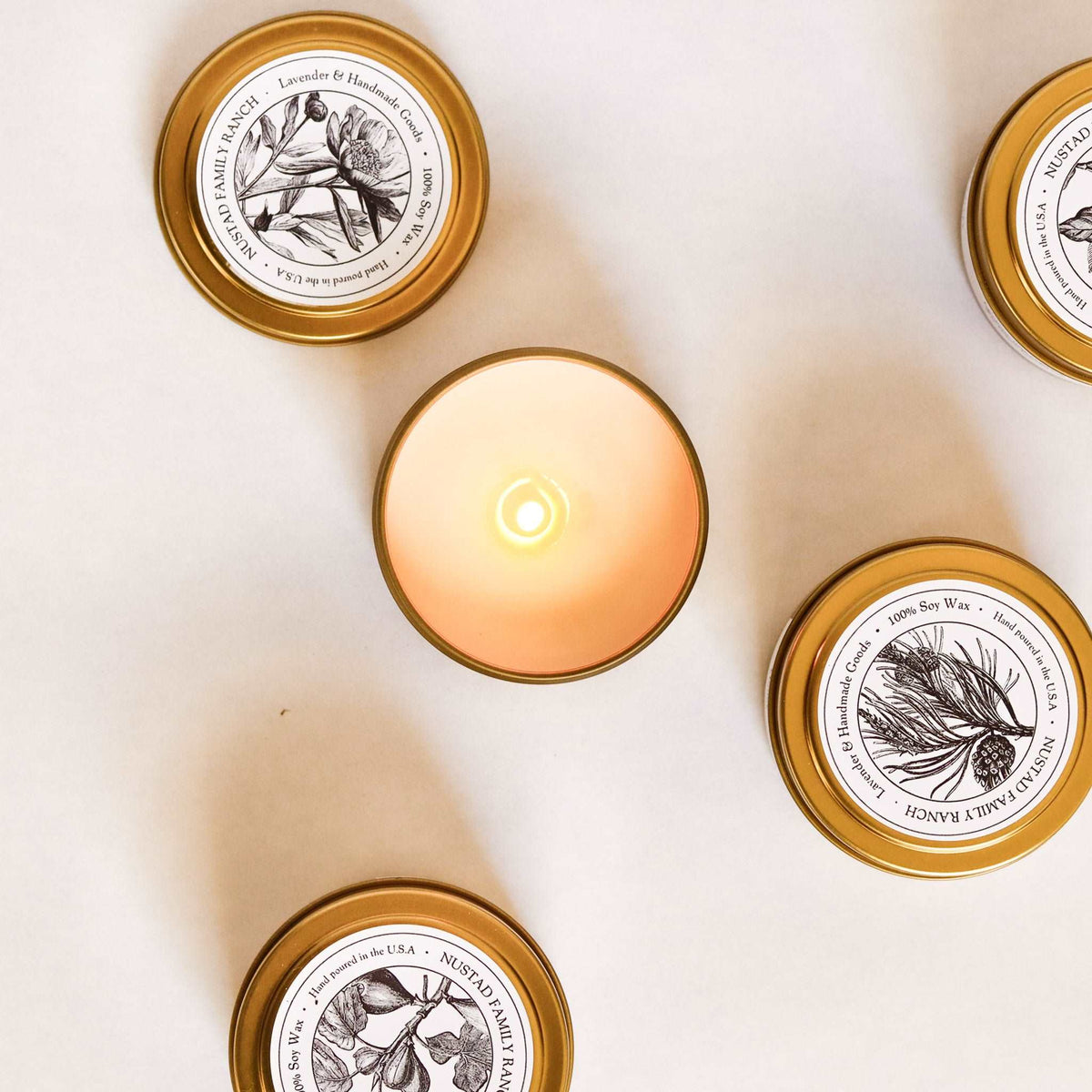 Farmhouse tin candle lids and a lit candle in a gold-rim tin