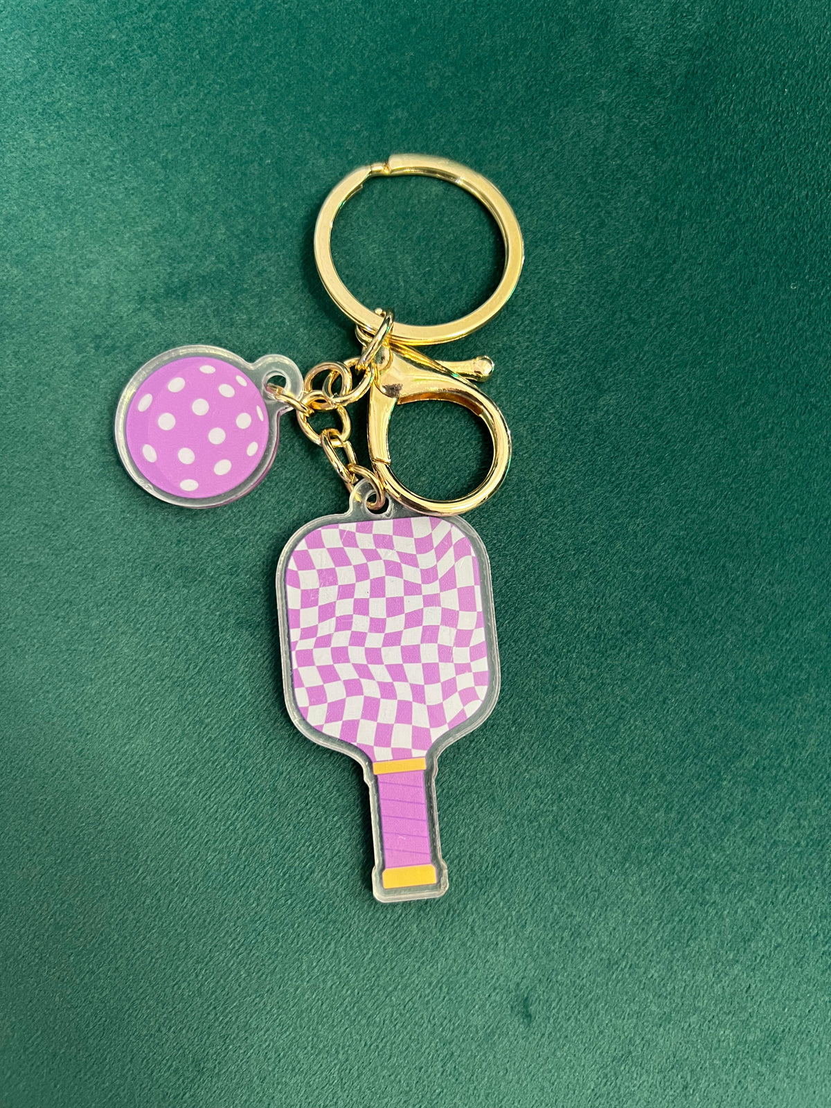 Acrylic pickleball paddle keychain with a pink checkered pattern and matching dotted ball charm.