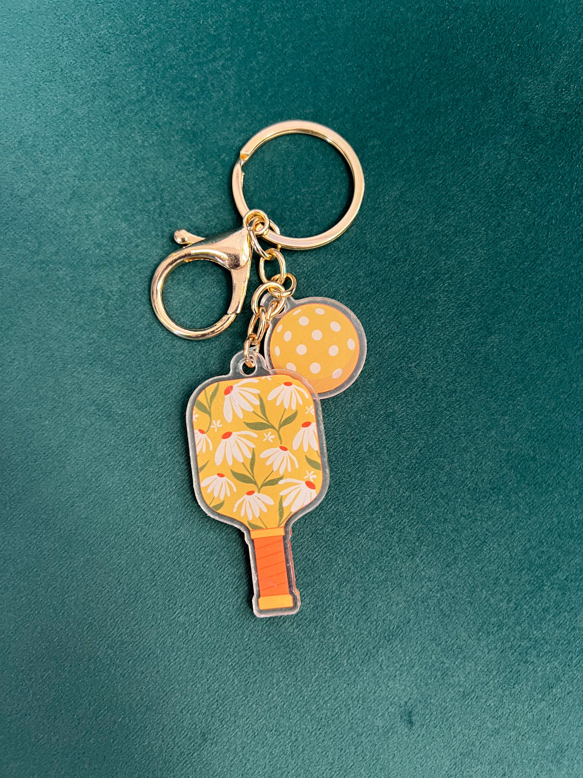 Acrylic pickleball paddle keychain with yellow floral print and a matching dotted ball charm.