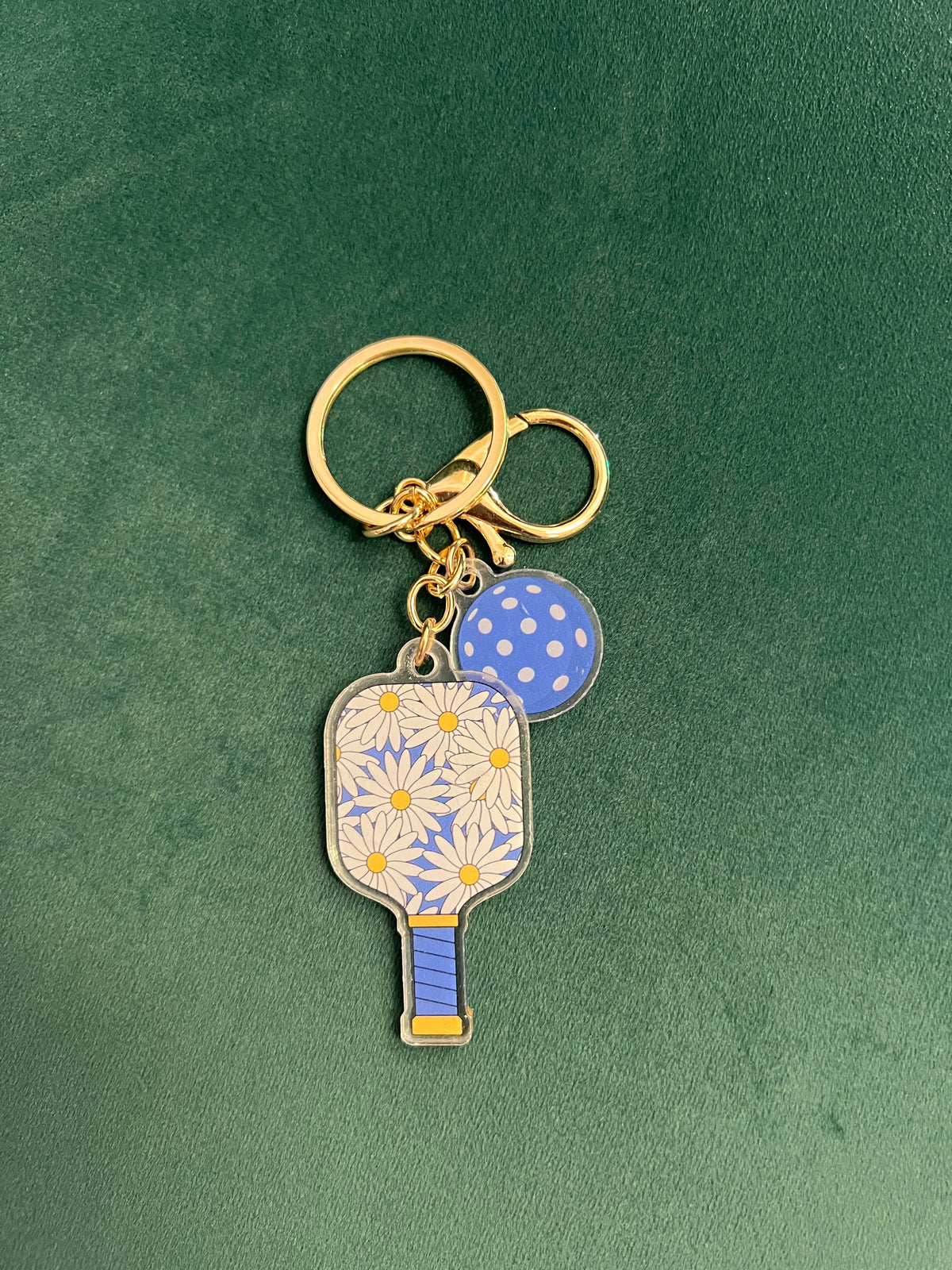 Acrylic pickleball paddle keychain with a daisy-print paddle and blue ball charm