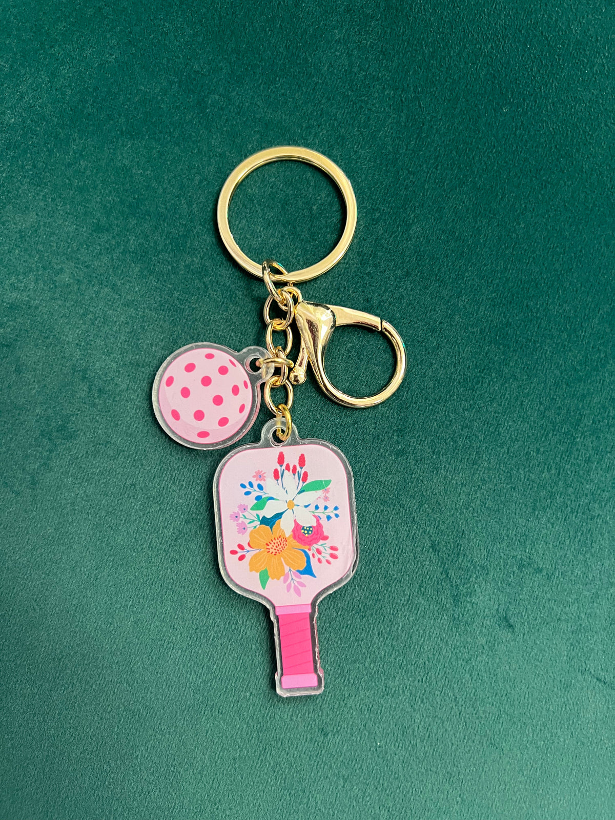 Acrylic pickleball paddle keychain with a pale pink floral paddle and pink-dotted ball charm