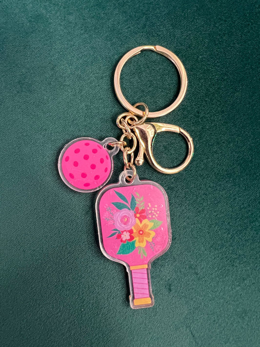 Acrylic pickleball paddle keychain with pink floral paddle and matching perforated ball charm