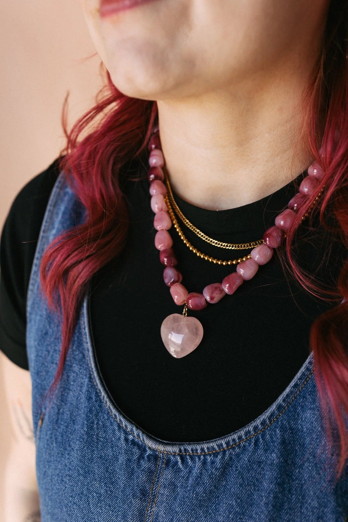 Pink jade bead necklace with a pale heart pendant, worn at the neckline