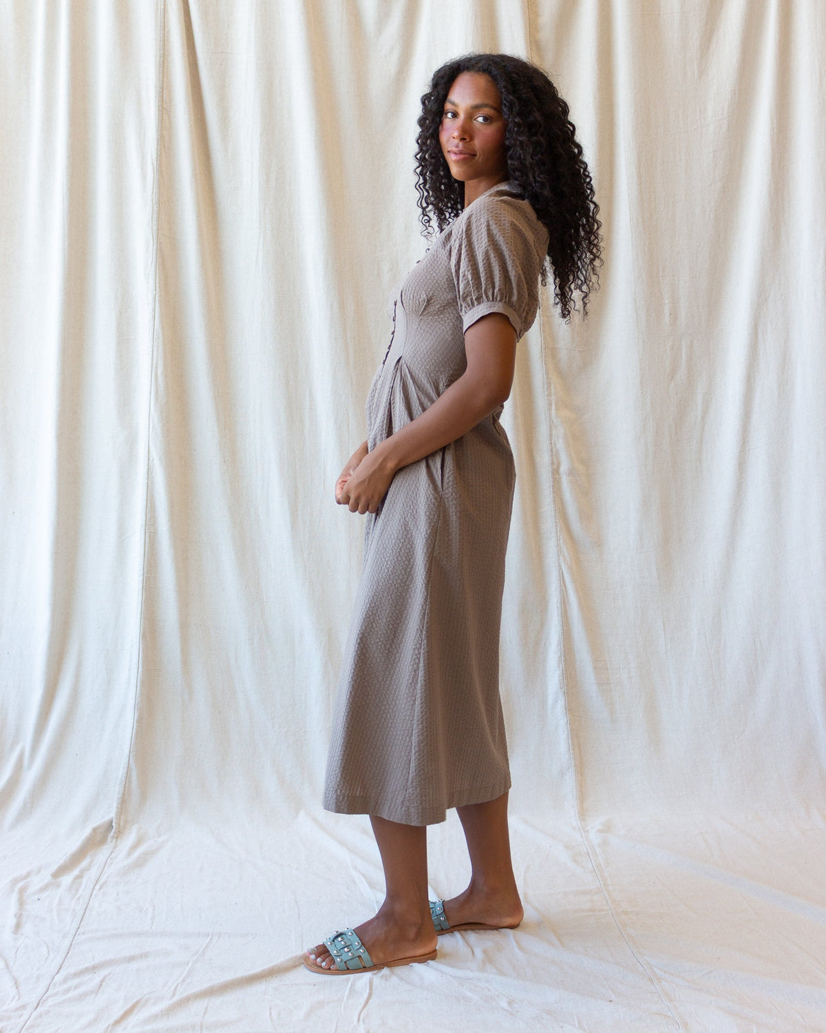 Brown midi field dress in side view with short puff sleeves and button-front placket