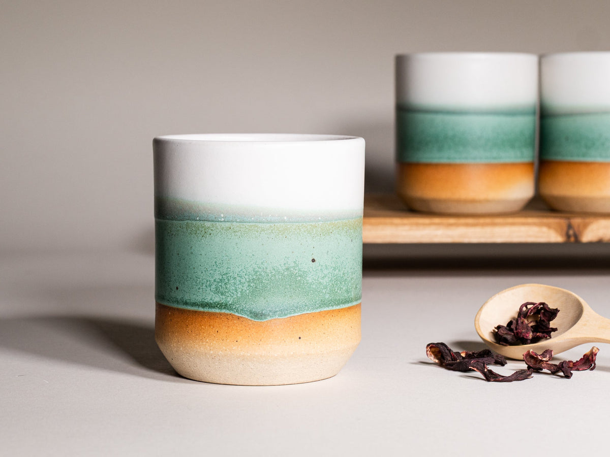 Green and white stoneware smoothie cup, 14 oz, with stacked cups in background.