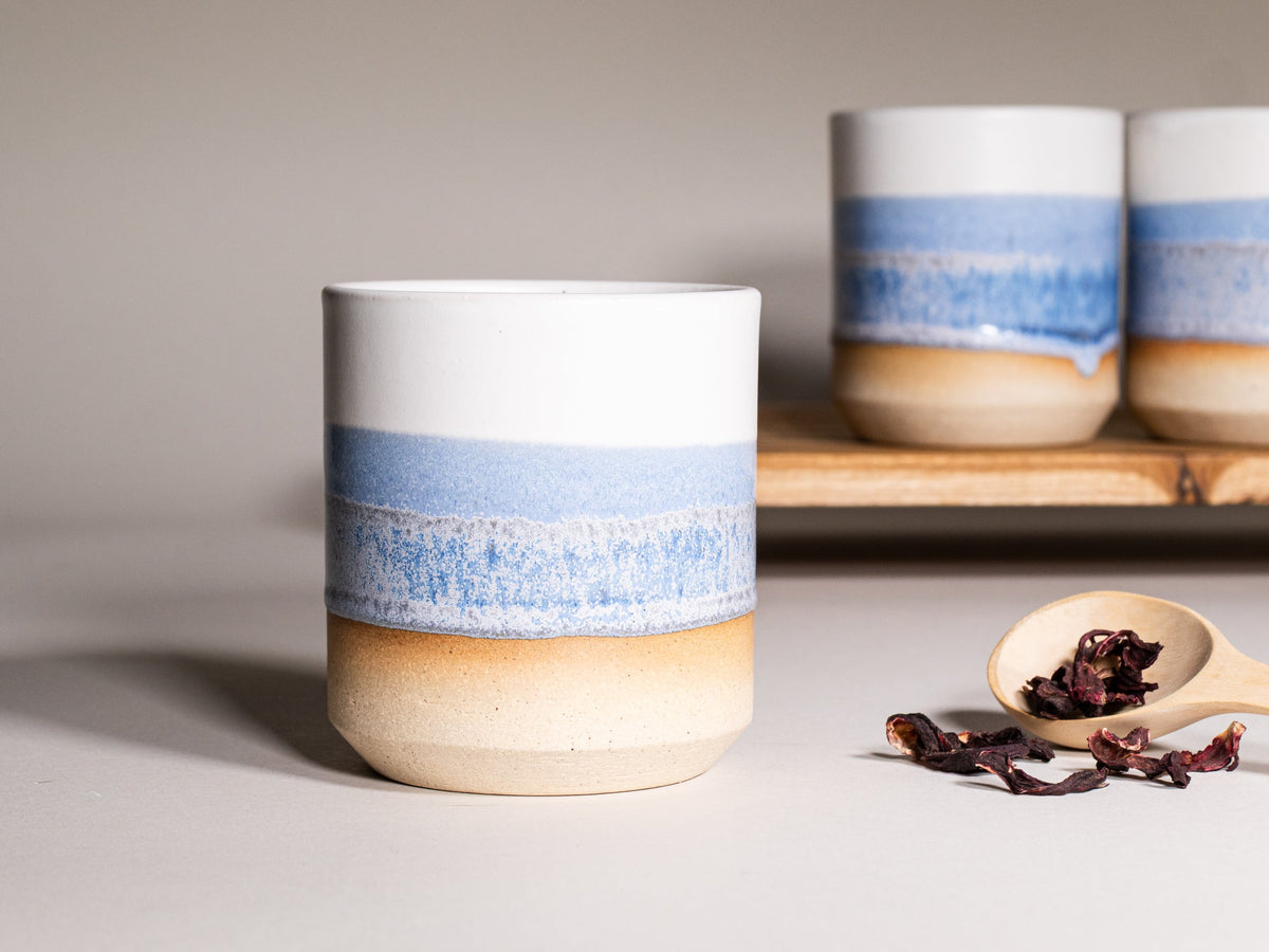 Stoneware smoothie cup with blue band and tan base, speckled glaze, front view